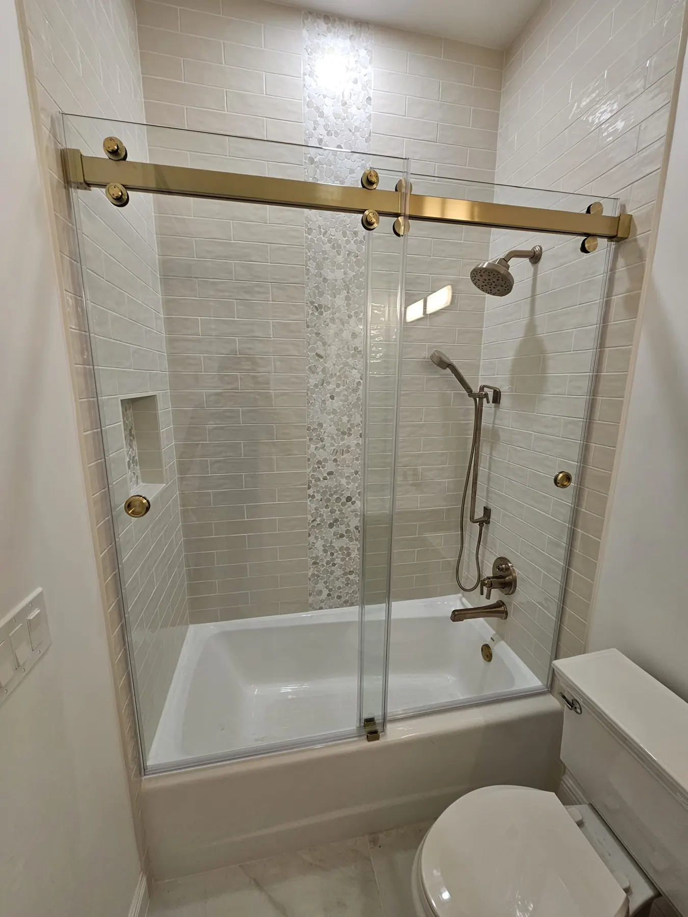 after frameless sliding shower glass with brushed gold hardware in Southwest Florida