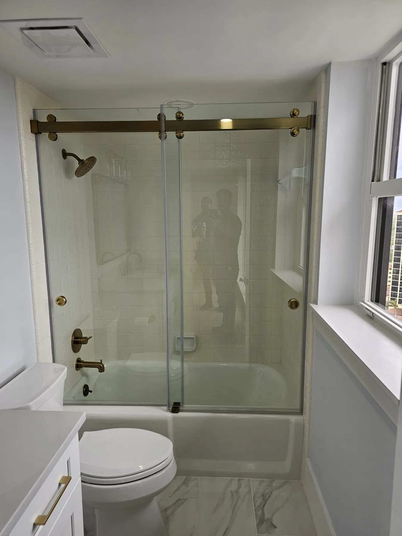 after frameless sliding shower glass with brushed gold hardware in Southwest Florida