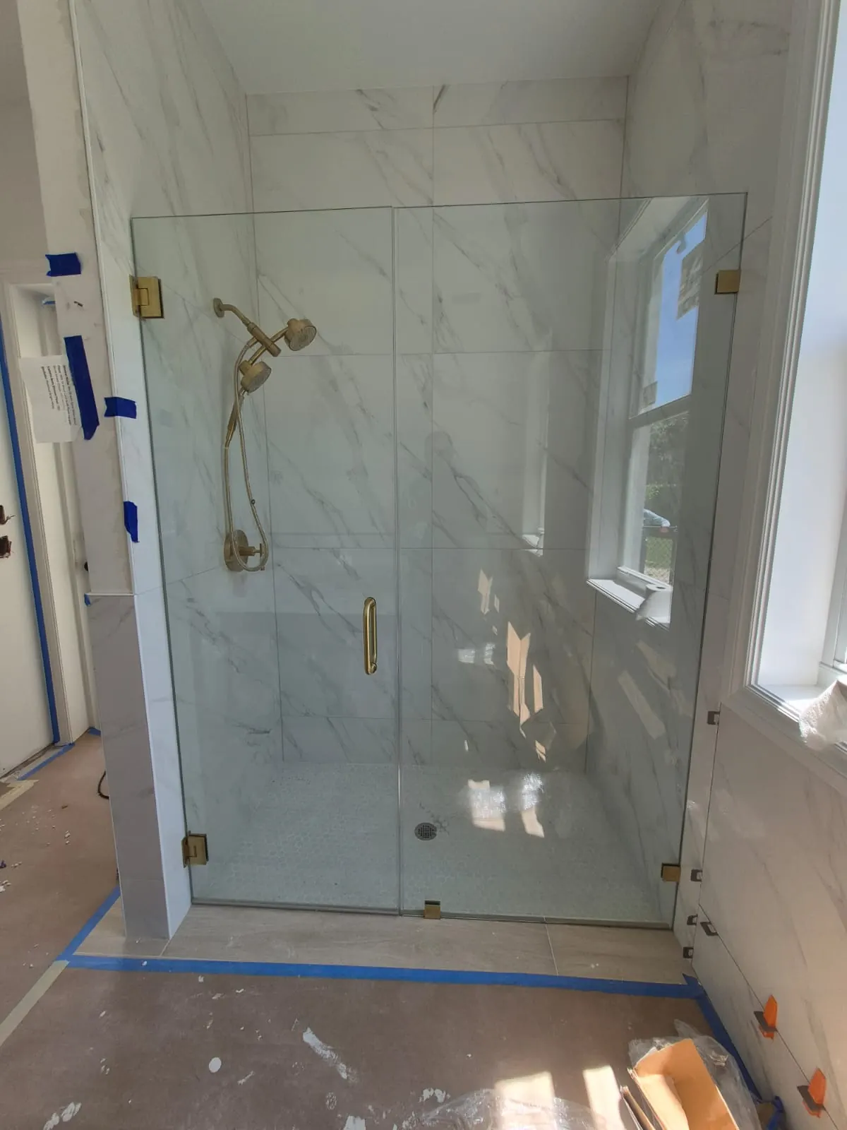 after frameless swing shower glass with brushed gold hardware in Southwest Florida