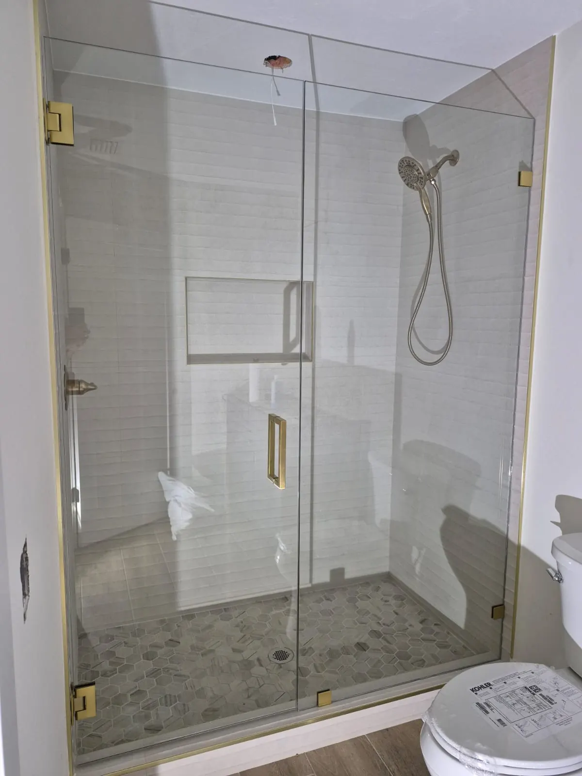after frameless swing shower glass with brushed gold hardware in Southwest Florida